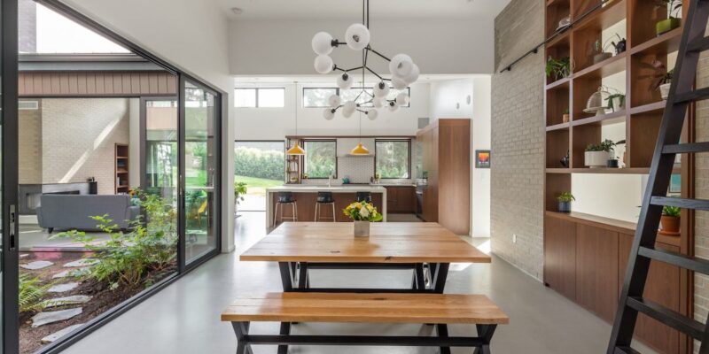 Custom wood bench dining table in a warm, modern home with the kitchen in the background, designed for family living and connection to nature.
