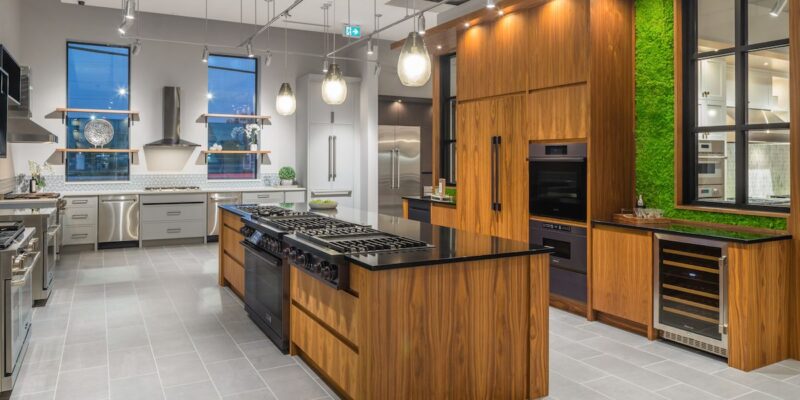 A staged woodgrain kitchen with a modern twist. Black stone countertops and dark finish appliances.