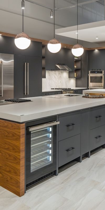 A clean modern industrial kitchen with large stone island and pendant lighting.