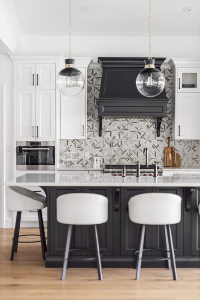 A freshly renovated greyscale kitchen with tile backsplash and stone kitchen island.