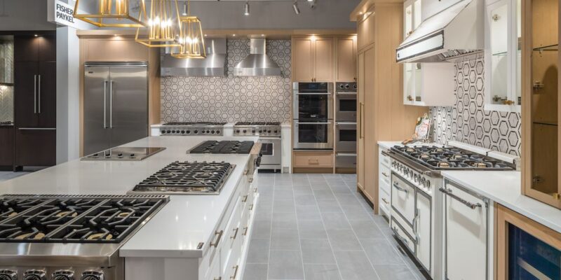 A newly renovated commercial kitchen featuring gas stove tops, pendant lighting, and new fixtures.