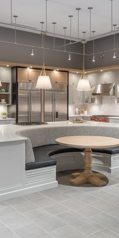 A round chef's table in the middle of a large newly renovated commercial kitchen.