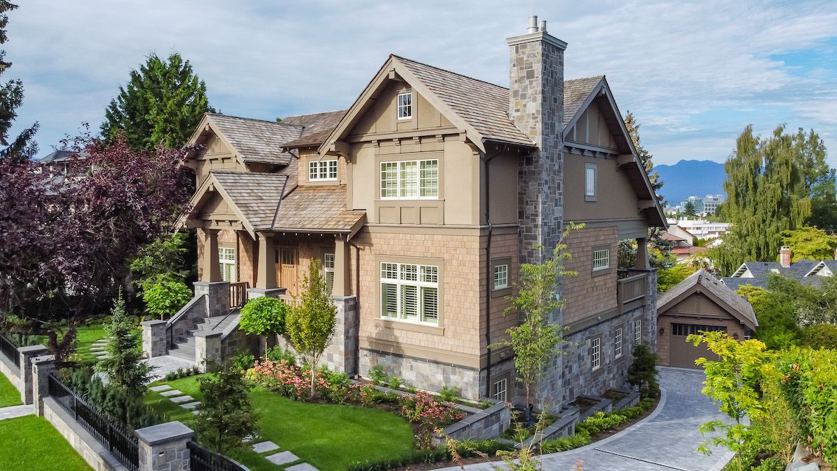 Exterior of a new custom-built heritage-style home in Shaughnessy, featuring Georgian paned windows, stone skirting, and board-and-batten gable accents, blending seamlessly with its historic surroundings.